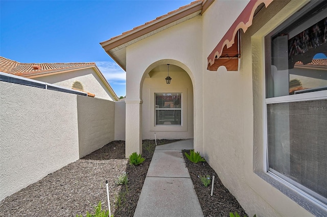 entrance to property featuring fence and stucco siding