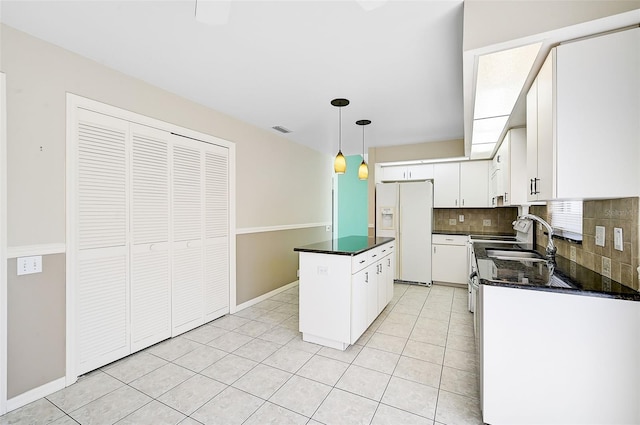 kitchen with a kitchen island, visible vents, white cabinets, white fridge with ice dispenser, and tasteful backsplash