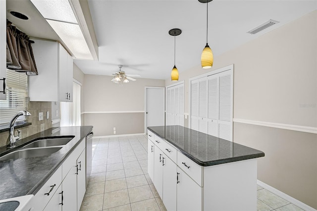 kitchen with light tile patterned flooring, a sink, visible vents, stainless steel dishwasher, and tasteful backsplash