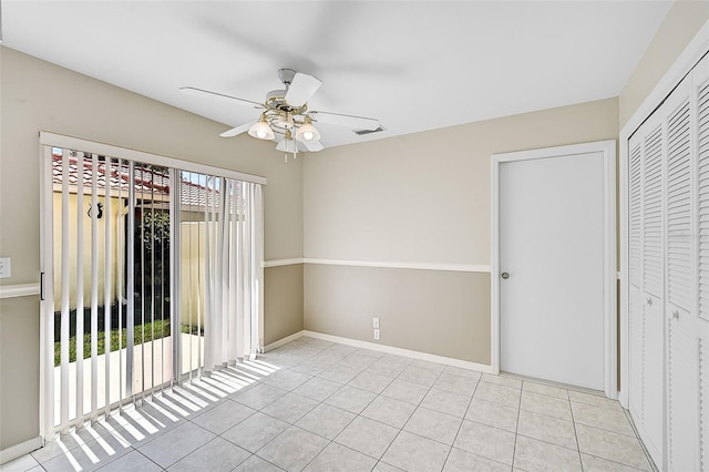 unfurnished bedroom featuring light tile patterned flooring, a ceiling fan, visible vents, baseboards, and a closet