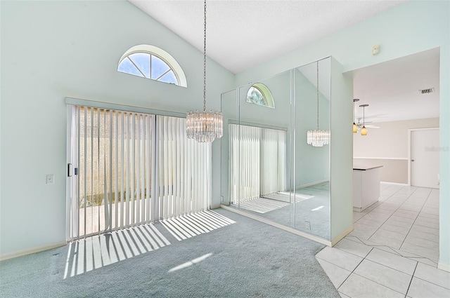 unfurnished room with carpet floors, visible vents, a textured ceiling, high vaulted ceiling, and ceiling fan with notable chandelier