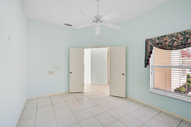 spare room with baseboards, light tile patterned flooring, visible vents, and a ceiling fan