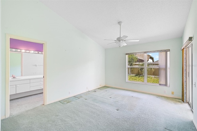 unfurnished bedroom with baseboards, lofted ceiling, carpet, a textured ceiling, and a sink