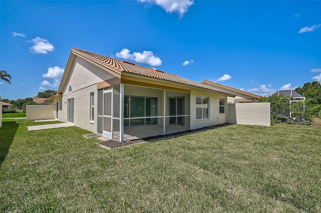 rear view of property featuring a sunroom, a lawn, and fence