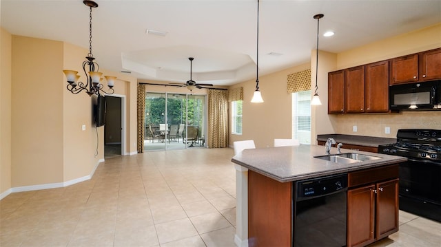 kitchen with black appliances, pendant lighting, a raised ceiling, and a kitchen island with sink