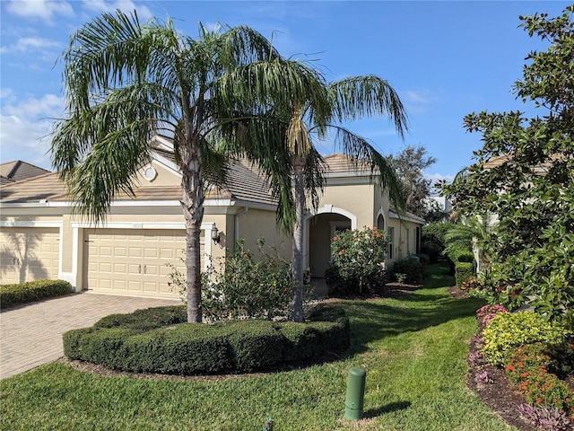 view of front of house featuring a garage, a front yard, decorative driveway, and stucco siding