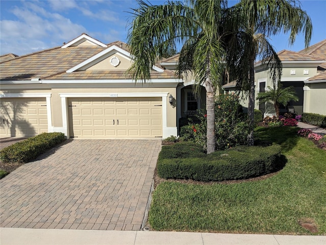 4830 Maymont Park Cir, Bradenton, FL 34203 - view of front of house with decorative driveway, a tile roof, stucco siding, an attached garage, and a front lawn