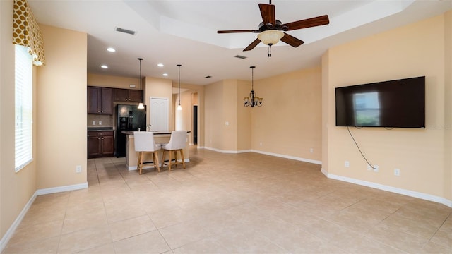 unfurnished living room featuring recessed lighting, a raised ceiling, visible vents, baseboards, and ceiling fan with notable chandelier