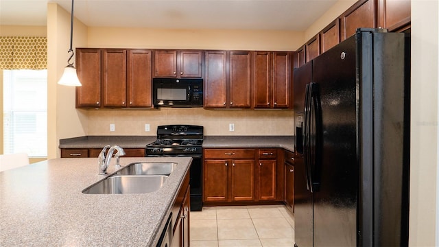 kitchen featuring decorative light fixtures, light tile patterned floors, dark countertops, a sink, and black appliances