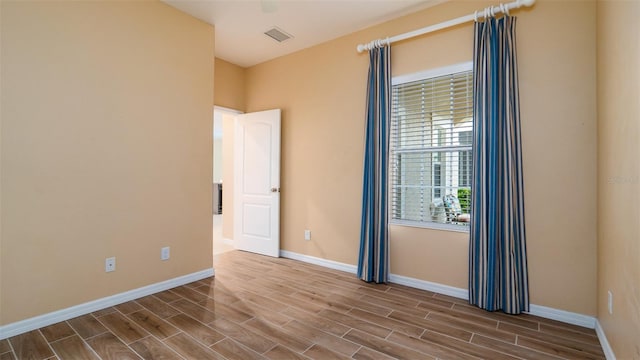 empty room featuring wood tiled floor, visible vents, and baseboards