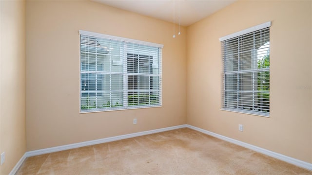 unfurnished room with baseboards and light colored carpet