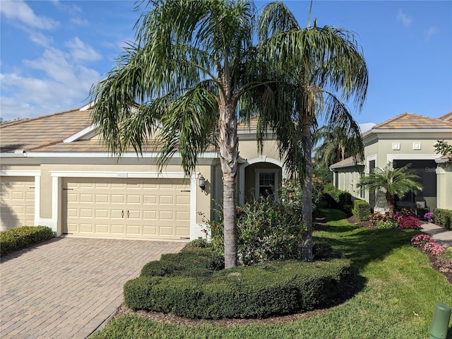 view of front of house featuring a garage, decorative driveway, a front lawn, and stucco siding