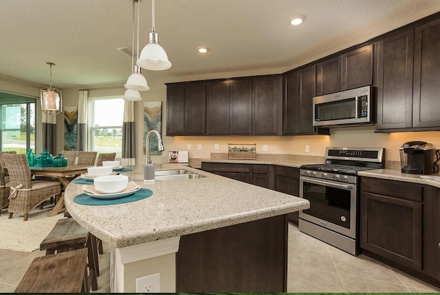 kitchen featuring appliances with stainless steel finishes, light tile patterned flooring, pendant lighting, and dark brown cabinetry