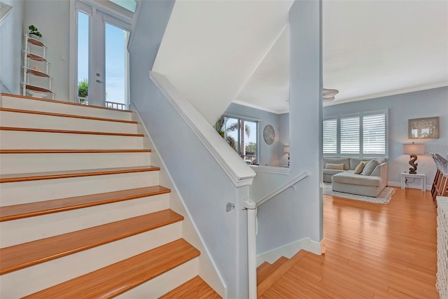 stairway with light hardwood / wood-style floors and ornamental molding