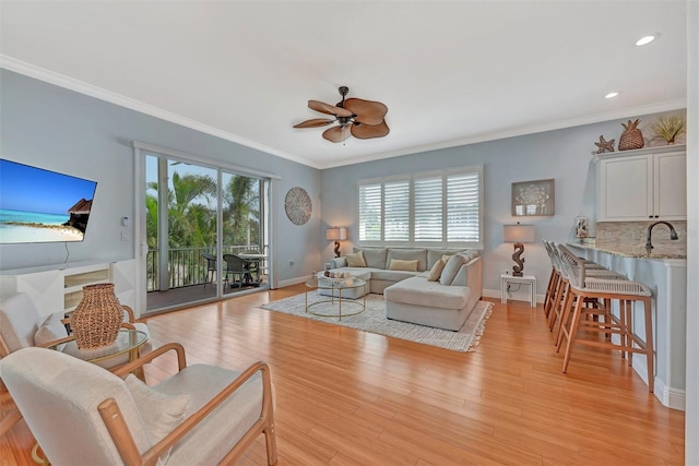 living room featuring sink, crown molding, ceiling fan, and light hardwood / wood-style floors