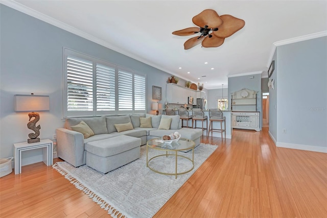 living room featuring ornamental molding, light wood-type flooring, and ceiling fan