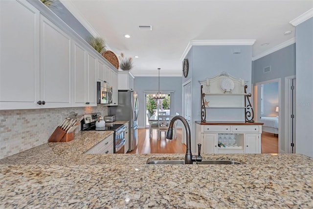 kitchen featuring appliances with stainless steel finishes, sink, light stone counters, backsplash, and light wood-type flooring