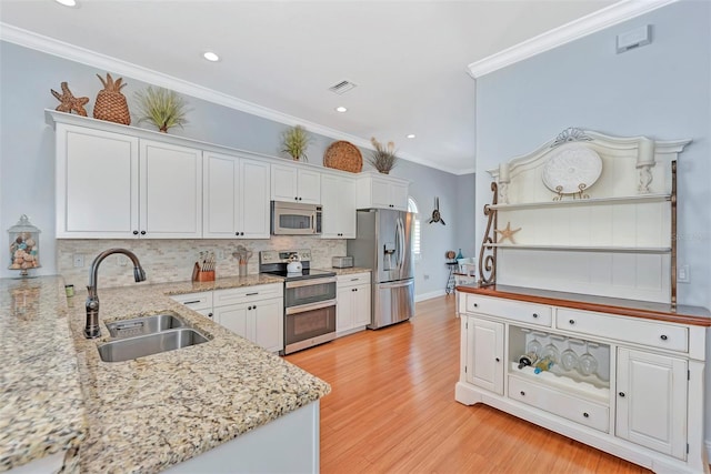 kitchen with stainless steel appliances, light hardwood / wood-style floors, and white cabinets