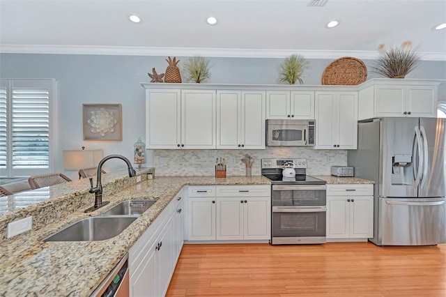 kitchen with decorative backsplash, light wood-type flooring, ornamental molding, sink, and appliances with stainless steel finishes