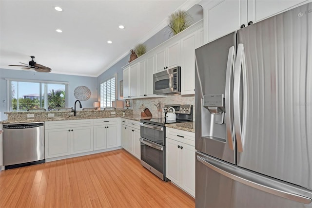 kitchen featuring white cabinetry, light wood-type flooring, ceiling fan, stainless steel appliances, and decorative backsplash