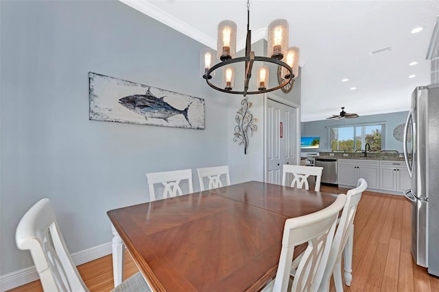 dining area with light hardwood / wood-style floors, sink, ornamental molding, and ceiling fan with notable chandelier