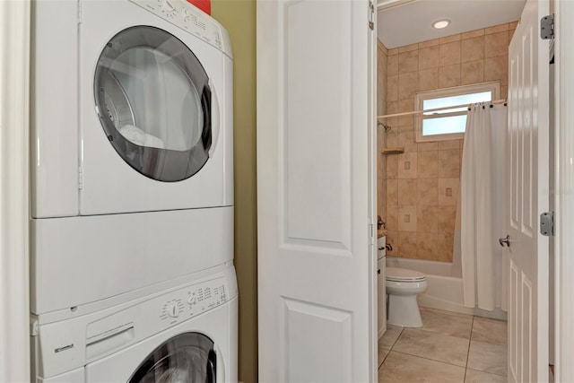 laundry area with stacked washer / dryer and light tile patterned floors