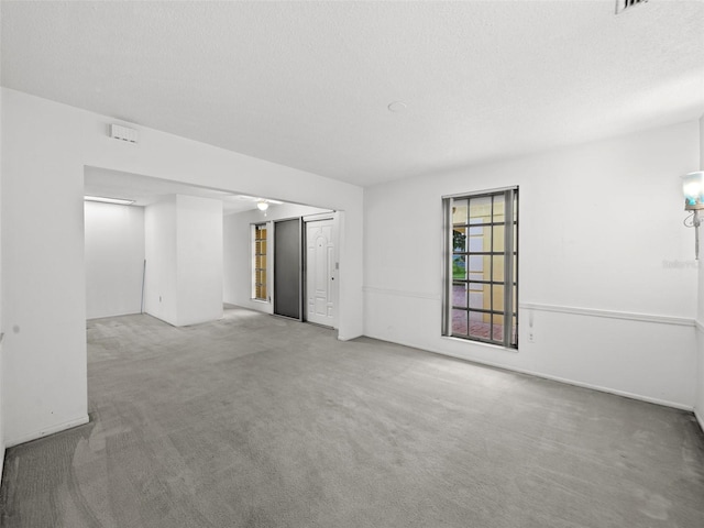 unfurnished living room with light colored carpet and a textured ceiling