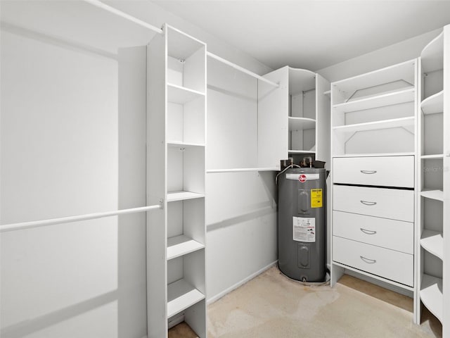 spacious closet featuring water heater and light colored carpet