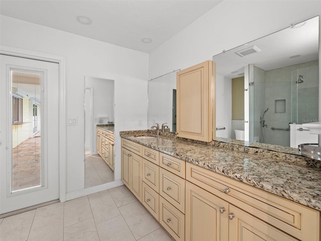 bathroom with tile patterned flooring, tiled shower, and vanity