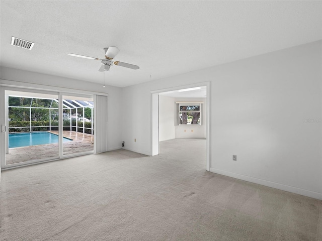 spare room featuring ceiling fan, a textured ceiling, and light carpet