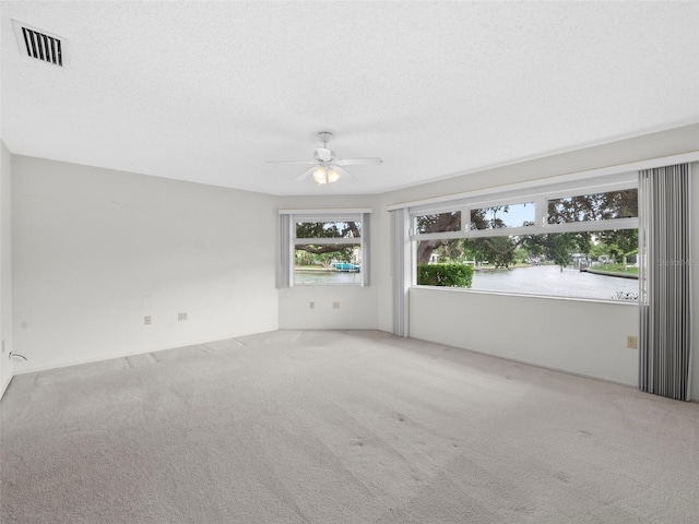 spare room with ceiling fan, a textured ceiling, and carpet flooring