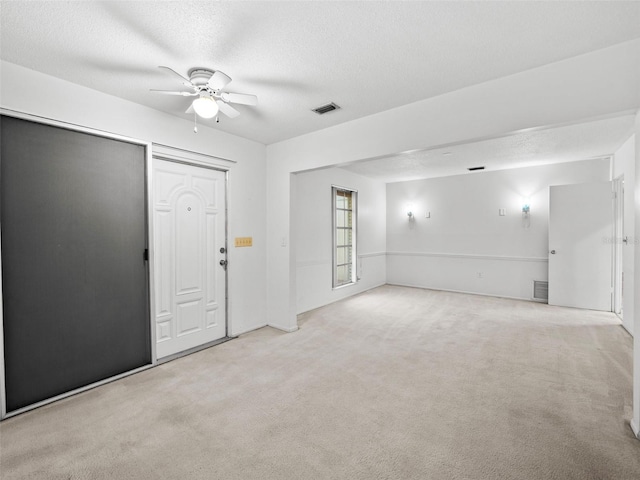 carpeted empty room with a textured ceiling and ceiling fan