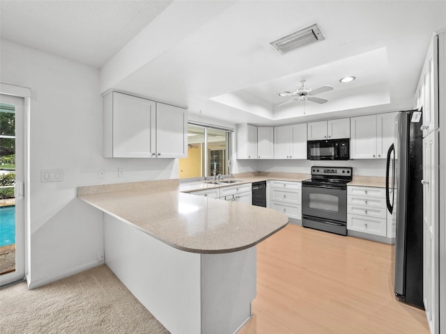 kitchen featuring ceiling fan, white cabinets, light hardwood / wood-style floors, kitchen peninsula, and black appliances