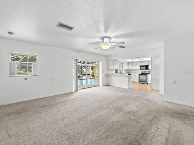 unfurnished living room featuring a textured ceiling, ceiling fan, and light colored carpet