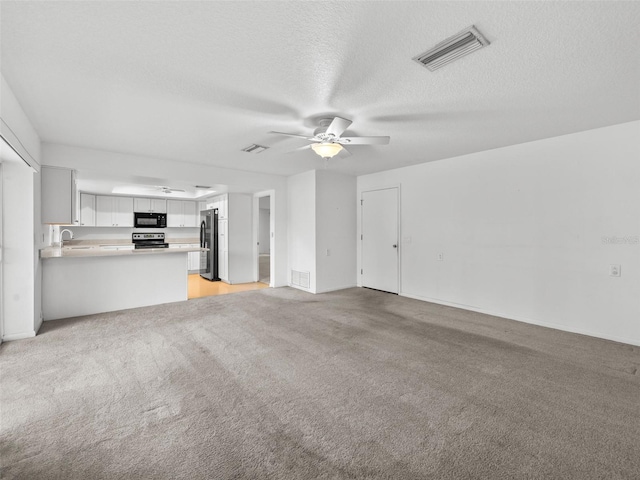 unfurnished living room with a textured ceiling, ceiling fan, light colored carpet, and sink