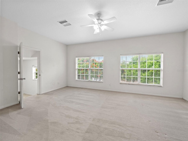 spare room with plenty of natural light, ceiling fan, and light colored carpet