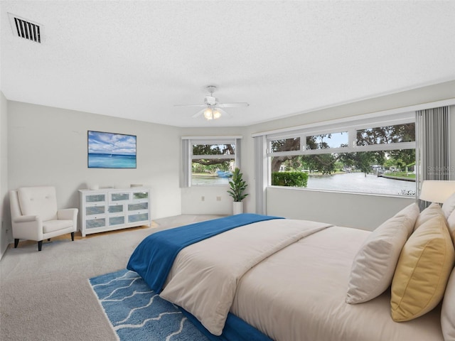 carpeted bedroom featuring ceiling fan and a textured ceiling