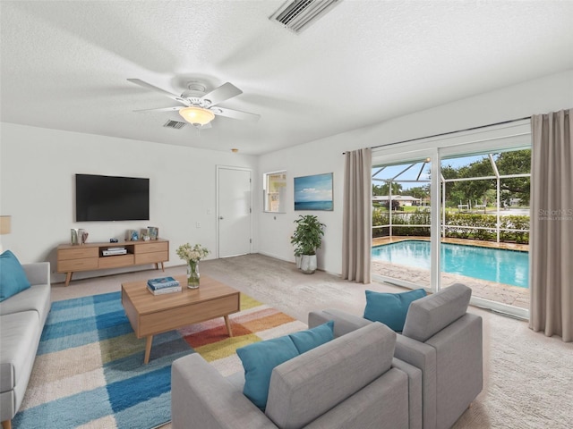 carpeted living room featuring ceiling fan and a textured ceiling