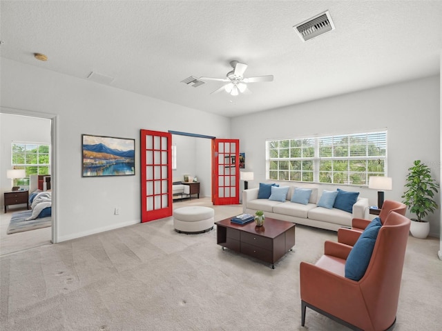 living room featuring a textured ceiling, carpet floors, and ceiling fan