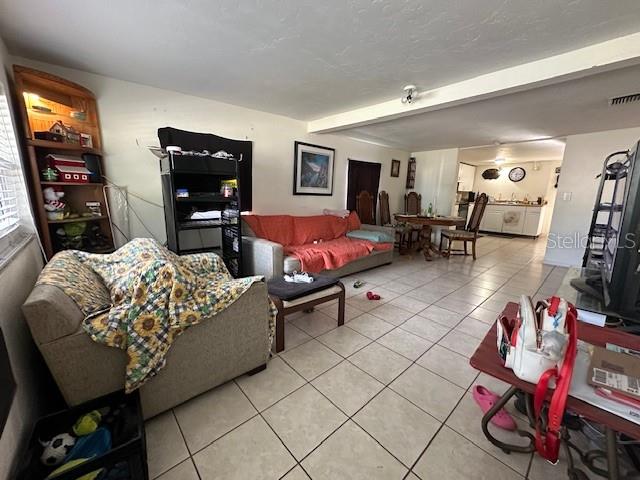 living room featuring light tile patterned flooring and beam ceiling