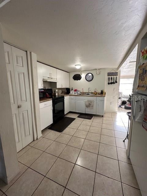 kitchen featuring white cabinets, electric range, light tile patterned flooring, and sink