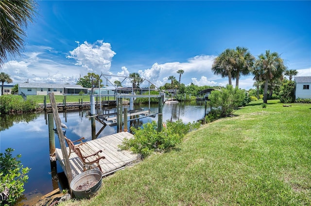 view of dock with a water view and a lawn