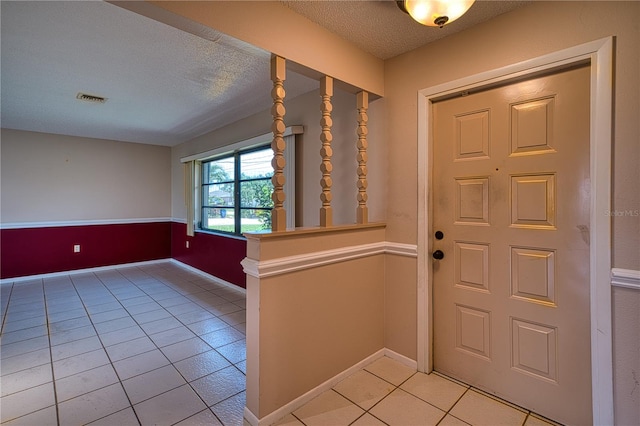 foyer entrance with a textured ceiling and light tile patterned flooring