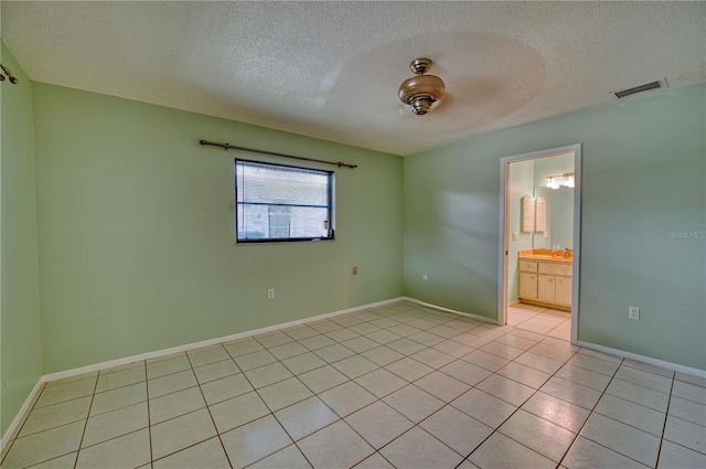 unfurnished room featuring a textured ceiling and light tile patterned floors