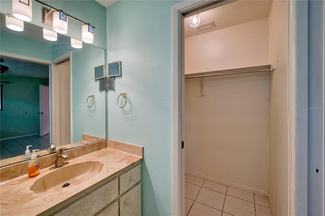 bathroom with tile patterned flooring, a textured ceiling, and vanity