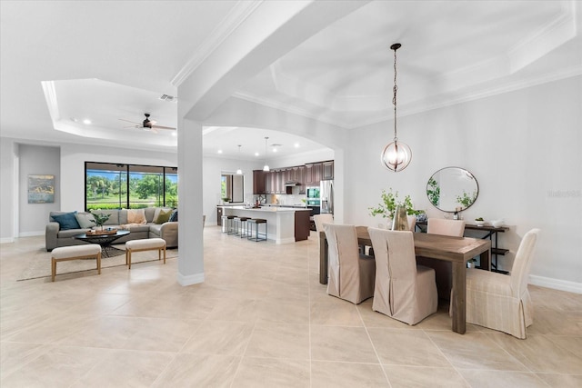 tiled dining room featuring crown molding, ceiling fan with notable chandelier, and a tray ceiling