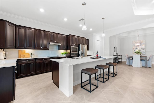 kitchen featuring pendant lighting, stainless steel appliances, a kitchen island with sink, and tasteful backsplash