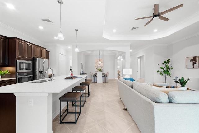 living room featuring light tile patterned flooring, sink, ornamental molding, a raised ceiling, and ceiling fan