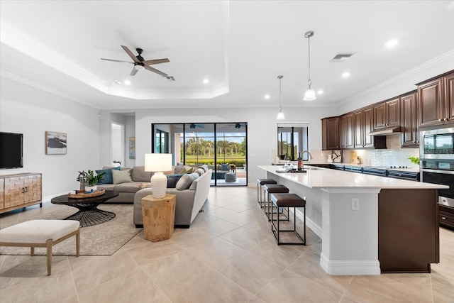 kitchen featuring dark brown cabinets, stainless steel appliances, a kitchen breakfast bar, ornamental molding, and a center island with sink