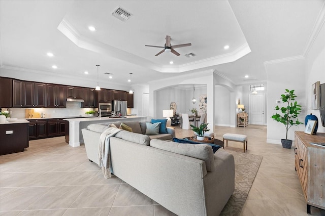 tiled living room featuring crown molding, a tray ceiling, and ceiling fan